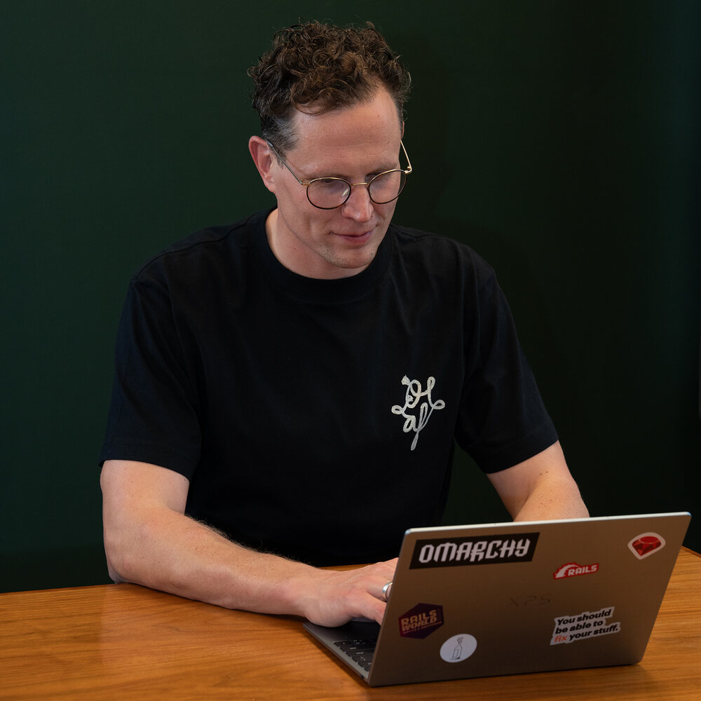Jankees van Woezik typing on his laptop, covered in stickers
